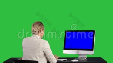 女人在办公室里看着显示器，绿色屏幕，Chroma键。 蓝色屏幕模拟显示。